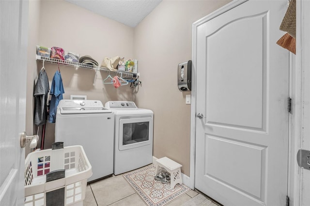 laundry room featuring washer and clothes dryer, light tile patterned flooring, and a textured ceiling