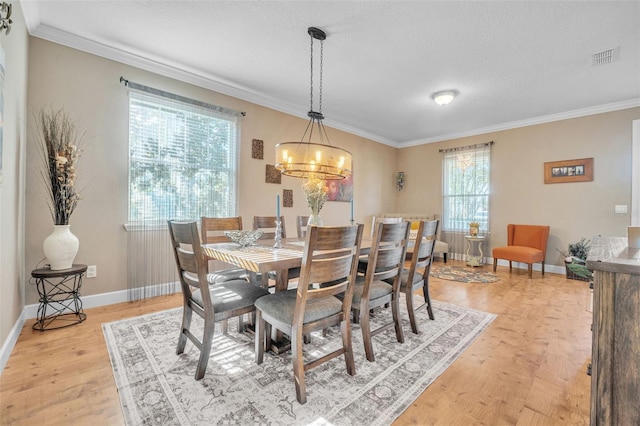 dining room with crown molding, light hardwood / wood-style floors, and a notable chandelier