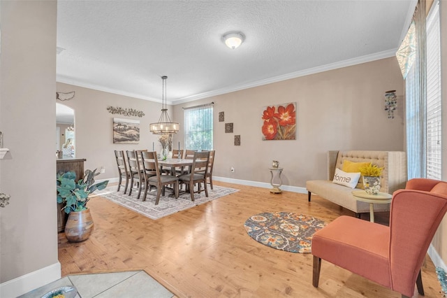 dining space with a chandelier, a textured ceiling, hardwood / wood-style flooring, and crown molding