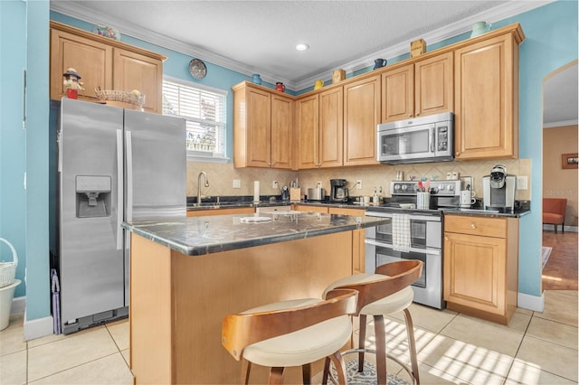 kitchen with stainless steel appliances, light tile patterned floors, a kitchen island, and crown molding