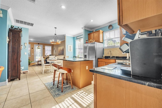 kitchen featuring light tile patterned flooring, hanging light fixtures, a kitchen island, stainless steel refrigerator with ice dispenser, and a kitchen bar