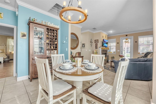 tiled dining area featuring crown molding, a fireplace, and an inviting chandelier