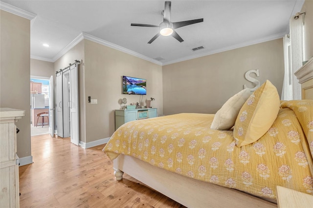 bedroom featuring light hardwood / wood-style floors, ceiling fan, crown molding, and a barn door