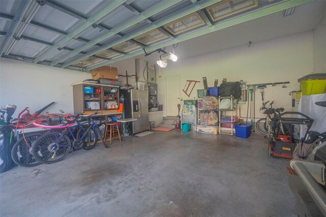 garage featuring a garage door opener and stainless steel fridge with ice dispenser