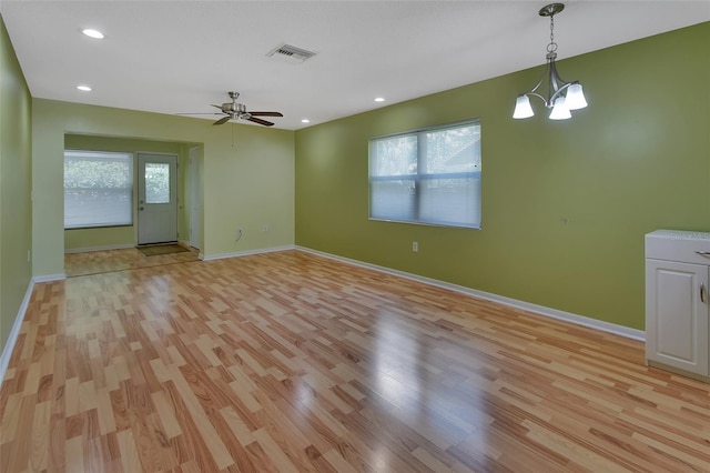 empty room with ceiling fan with notable chandelier and light wood-type flooring