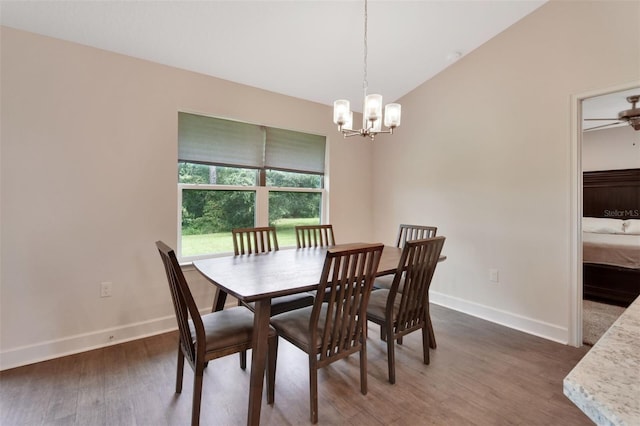 dining area featuring vaulted ceiling, dark hardwood / wood-style floors, and ceiling fan with notable chandelier