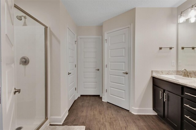 bathroom featuring wood-type flooring, an enclosed shower, vanity, and a textured ceiling