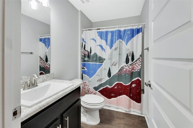 bathroom featuring vanity, toilet, curtained shower, and hardwood / wood-style floors