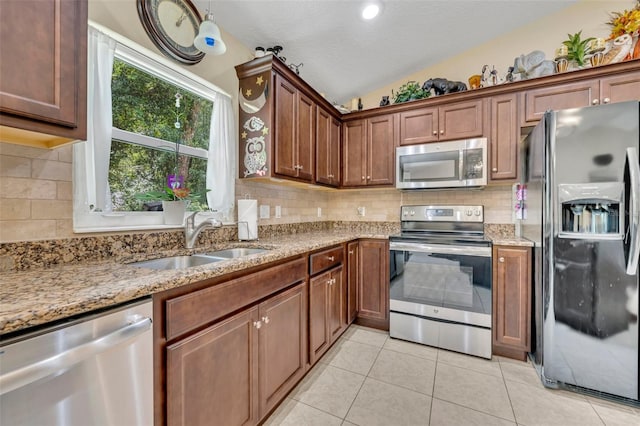 kitchen featuring stainless steel appliances, vaulted ceiling, sink, backsplash, and light tile patterned flooring