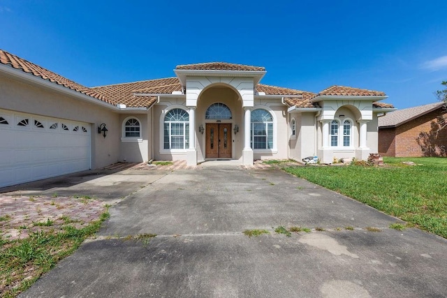 mediterranean / spanish-style house featuring a garage and a front yard