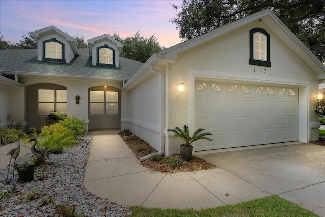 view of front of property with stucco siding, concrete driveway, a shingled roof, and an attached garage