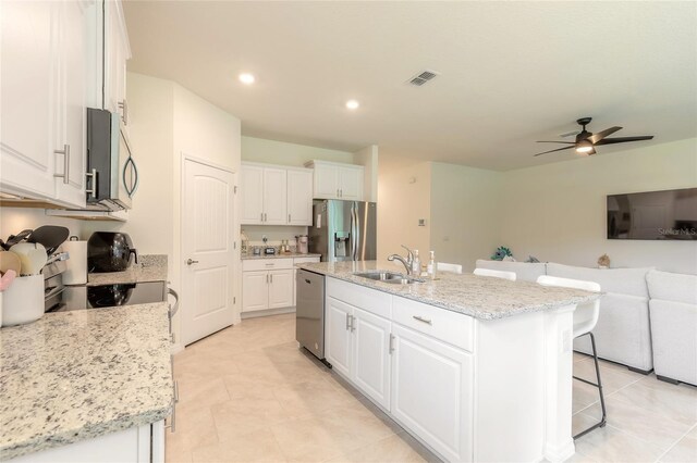 kitchen featuring sink, white cabinets, a kitchen island with sink, light stone counters, and stainless steel appliances