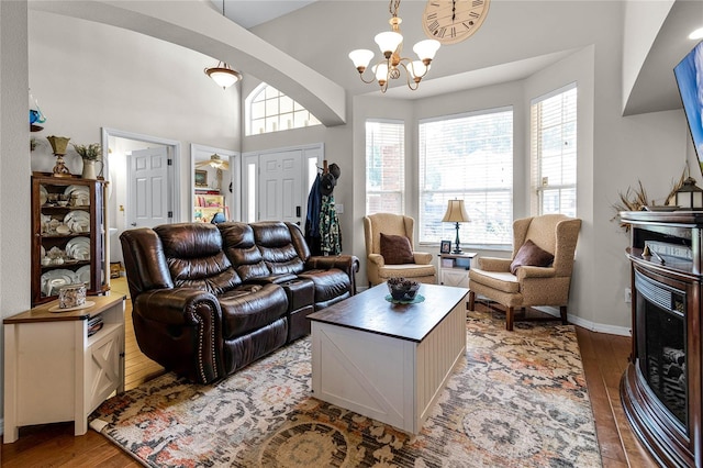 living room with a high ceiling, wood-type flooring, and a notable chandelier