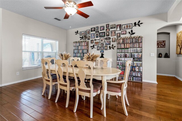 dining area featuring ceiling fan, dark wood-type flooring, and a textured ceiling