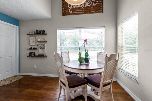 dining space with a textured ceiling and dark hardwood / wood-style floors