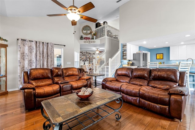 living room featuring light hardwood / wood-style flooring, ceiling fan, and high vaulted ceiling