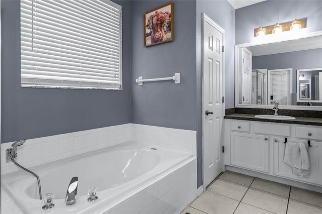 bathroom with tile patterned flooring, tiled tub, and vanity