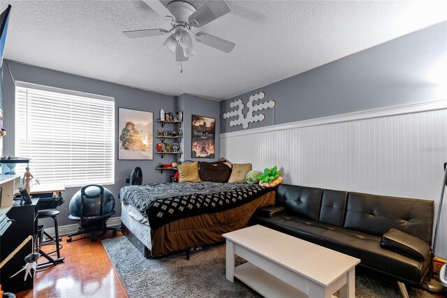 bedroom with hardwood / wood-style flooring, a textured ceiling, and ceiling fan