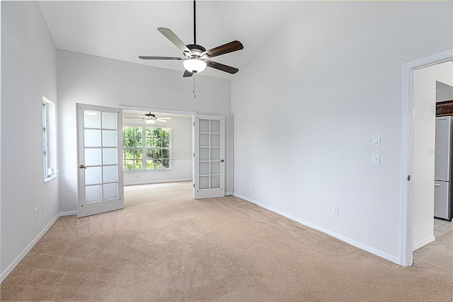 carpeted spare room featuring high vaulted ceiling, french doors, and ceiling fan