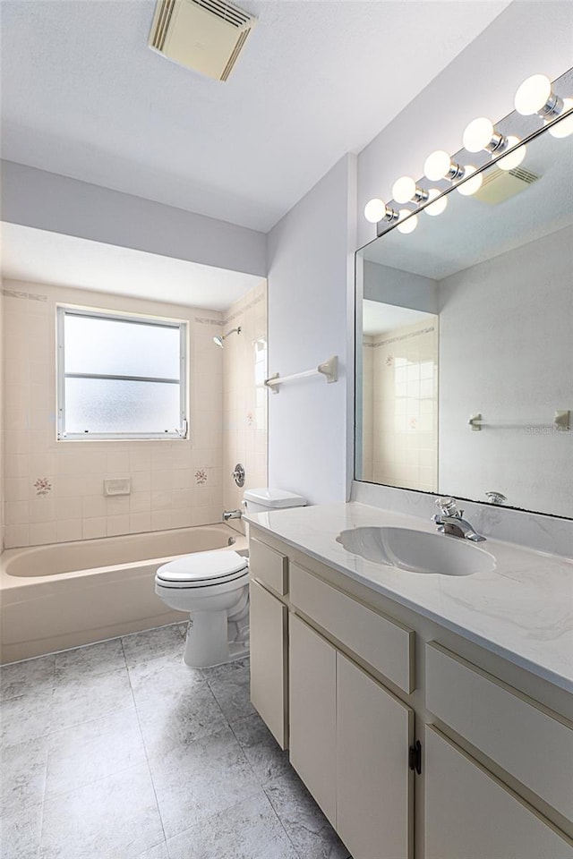 full bathroom with tile patterned flooring, toilet, vanity, and tiled shower / bath