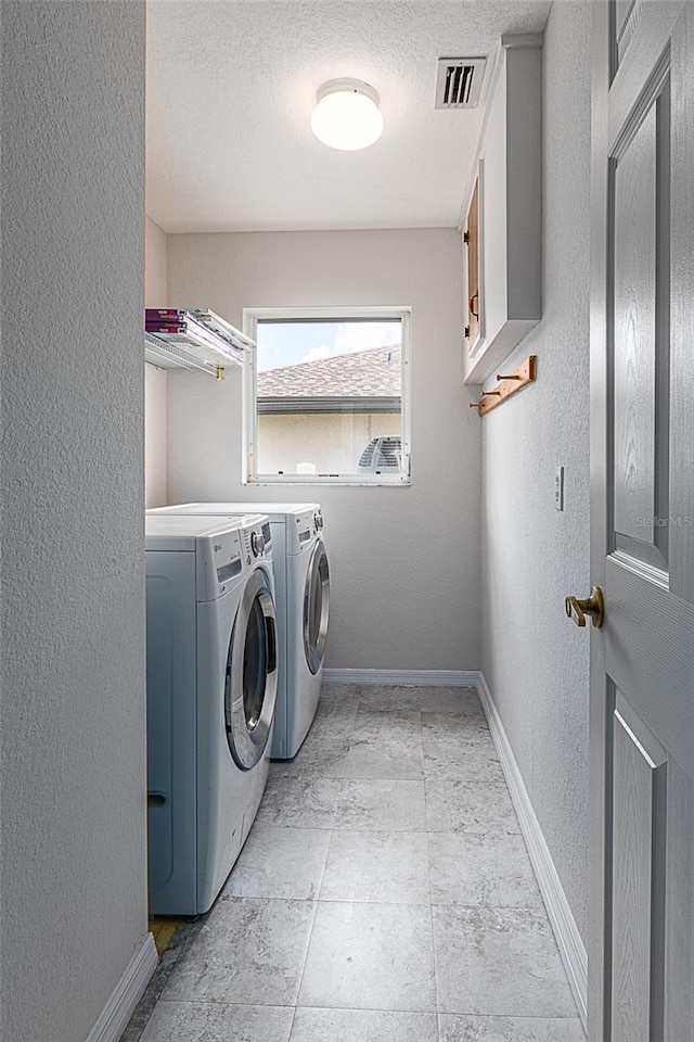 laundry room with light tile patterned flooring, cabinets, a textured ceiling, and washer and dryer