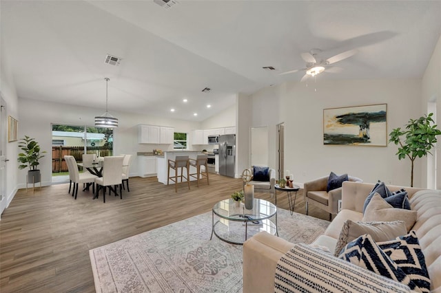 living room with light hardwood / wood-style flooring, high vaulted ceiling, and ceiling fan