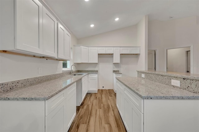 kitchen featuring sink, light hardwood / wood-style flooring, white cabinets, and light stone countertops