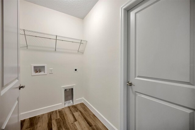 laundry area featuring electric dryer hookup, hookup for a washing machine, a textured ceiling, and hardwood / wood-style flooring