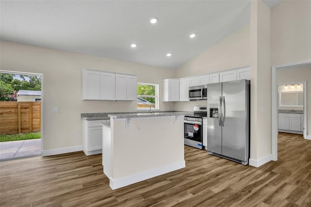 210 E Baxter St, De Leon Springs, FL 32130 - kitchen featuring appliances with stainless steel finishes, wood finished floors, white cabinets, a center island, and baseboards
