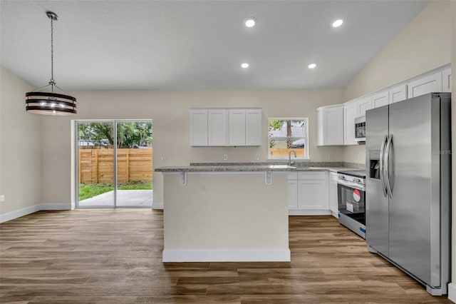 210 E Baxter St, De Leon Springs, FL 32130 - kitchen featuring stainless steel appliances, white cabinetry, wood finished floors, light stone countertops, and recessed lighting