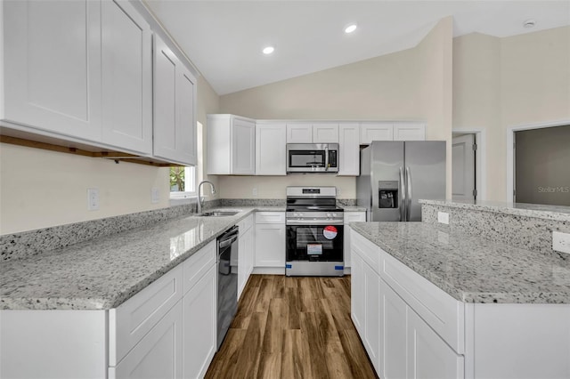 210 E Baxter St, De Leon Springs, FL 32130 - kitchen featuring stainless steel appliances, a sink, lofted ceiling, wood finished floors, and white cabinetry