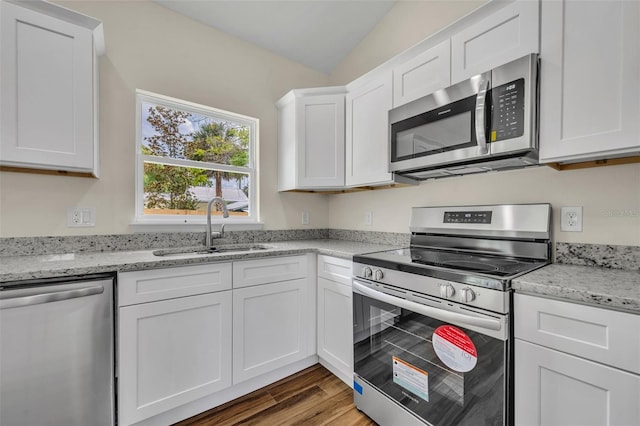 210 E Baxter St, De Leon Springs, FL 32130 - kitchen featuring appliances with stainless steel finishes, a sink, white cabinets, wood finished floors, and light stone counters