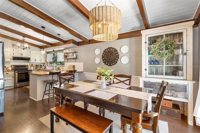 dining room featuring dark hardwood / wood-style floors, beamed ceiling, and a chandelier