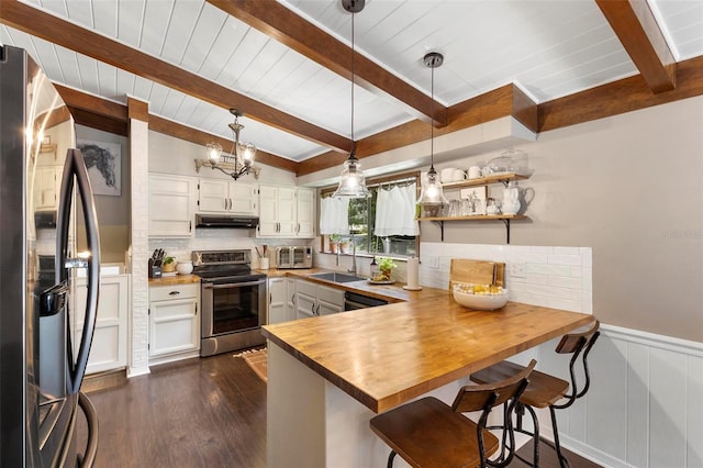 kitchen featuring white cabinets, dark hardwood / wood-style floors, stainless steel appliances, a kitchen breakfast bar, and decorative light fixtures