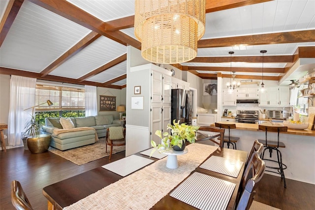 dining room featuring dark hardwood / wood-style floors, vaulted ceiling with beams, and a chandelier