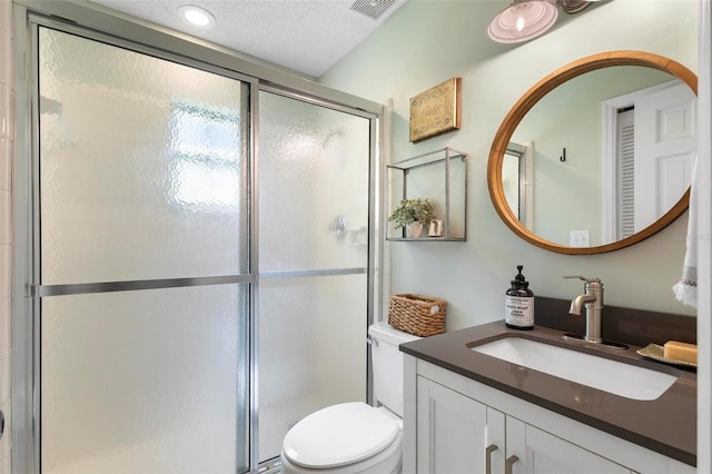 bathroom with a shower with shower door, toilet, vanity, and a textured ceiling