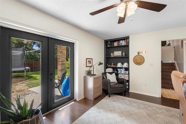 sitting room with french doors, dark hardwood / wood-style flooring, built in shelves, a textured ceiling, and ceiling fan