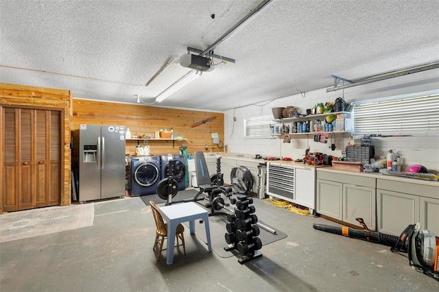 garage featuring stainless steel fridge with ice dispenser, separate washer and dryer, wood walls, a garage door opener, and a workshop area