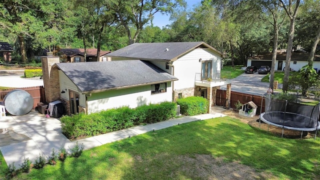 rear view of house featuring a garage, a trampoline, and a yard