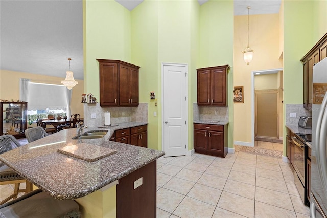 kitchen with a sink, hanging light fixtures, a kitchen breakfast bar, and light tile patterned floors