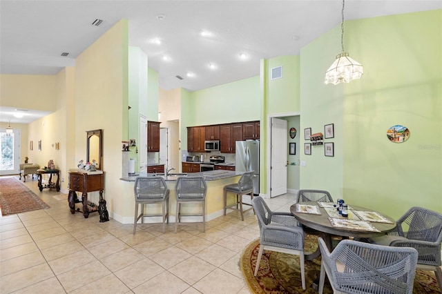 tiled dining area with an inviting chandelier, sink, and high vaulted ceiling