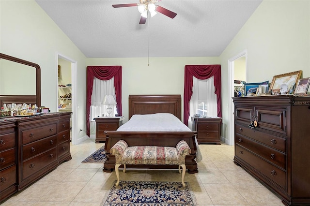 bedroom with ceiling fan, lofted ceiling, a textured ceiling, and light tile patterned floors