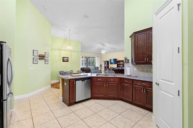 kitchen with stone countertops, hanging light fixtures, light tile patterned floors, kitchen peninsula, and stainless steel appliances