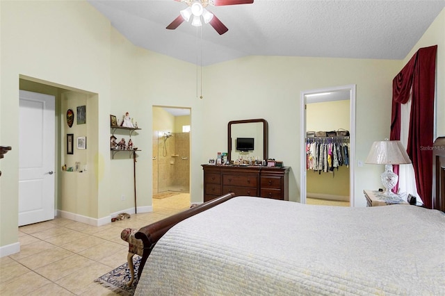 bedroom with lofted ceiling, ensuite bathroom, a walk in closet, a textured ceiling, and light tile patterned floors