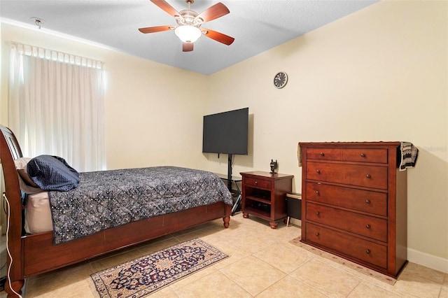 bedroom with a ceiling fan, baseboards, and light tile patterned floors