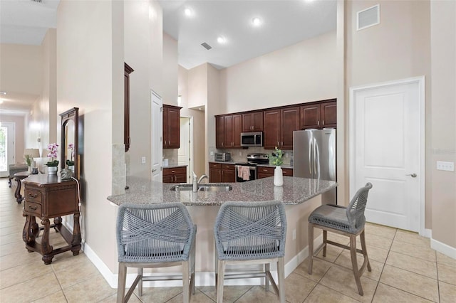 309 Chesham St, Ormond Beach, FL 32174 - kitchen with appliances with stainless steel finishes, a sink, a high ceiling, light stone countertops, and a breakfast bar area