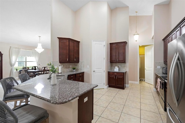 309 Chesham St, Ormond Beach, FL 32174 - kitchen with appliances with stainless steel finishes, a kitchen bar, decorative backsplash, a sink, and decorative light fixtures