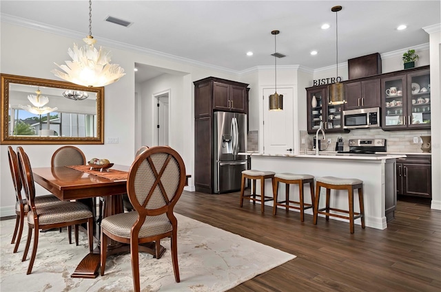 dining area with a chandelier, sink, crown molding, and dark hardwood / wood-style floors