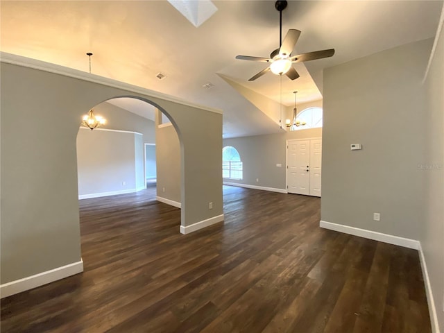 empty room with ceiling fan with notable chandelier, vaulted ceiling, and dark hardwood / wood-style floors