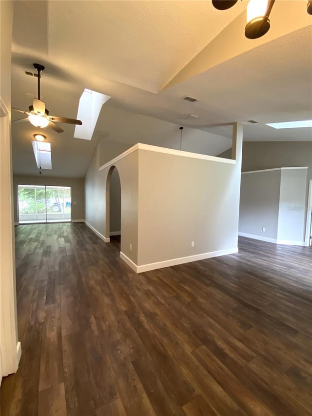 interior space featuring lofted ceiling with skylight, dark wood-type flooring, and ceiling fan